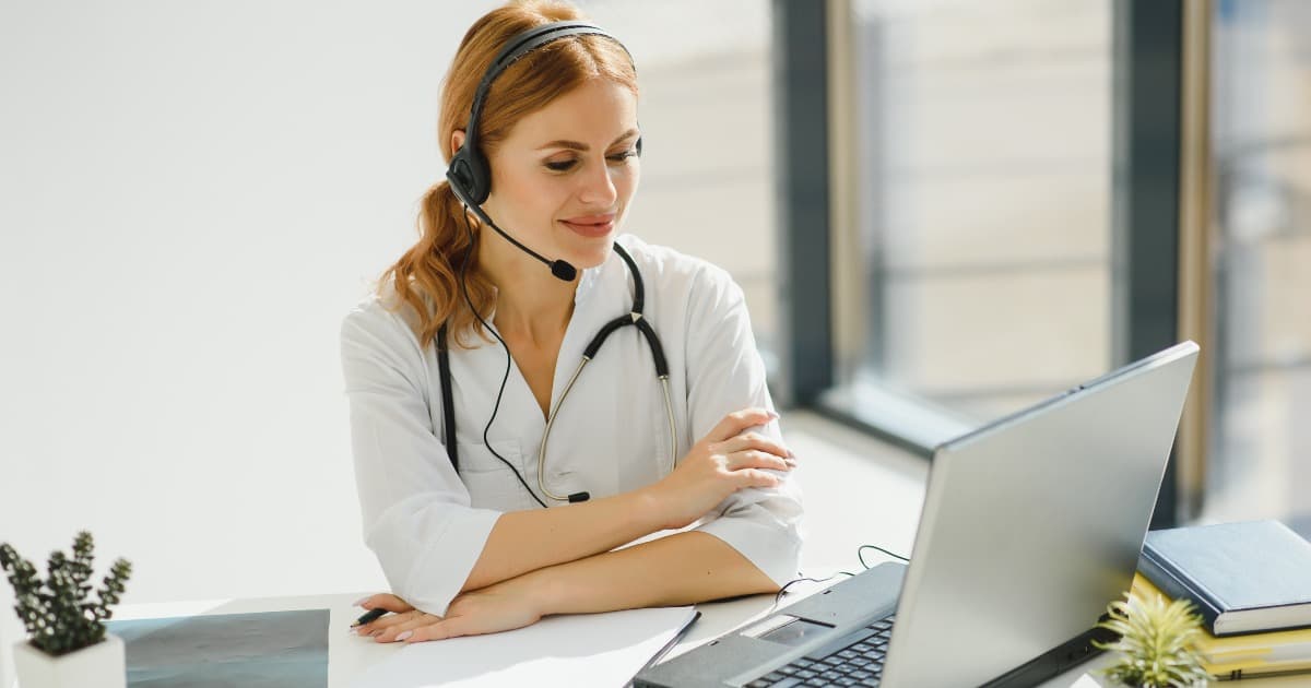 Young female doctor talking to patient online from medical office. Physician consulting client on video chat laptop at hospital.
